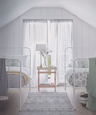 Holiday-style guest bedroom with curtains and metal-framed beds.