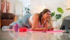 Woman smiles as she holds plank position in a living space