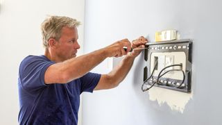 Man mounting TV on wall