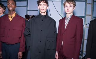 Three models stood next to each other with black and red jackets on