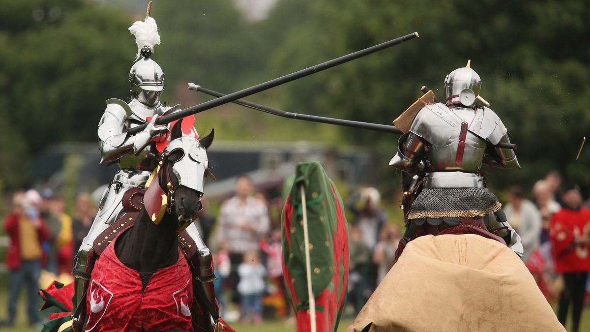 Two re-enactors jousting on horseback in medieval knights&#039; armour