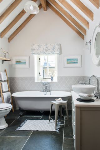 a new bathroom in a renovated home with vaulted ceiling and freestanding bath, white good and a black tiled floor