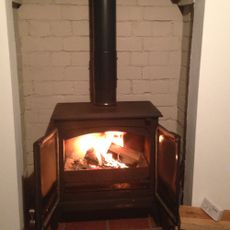 Esse log burning stove within tall fireplace