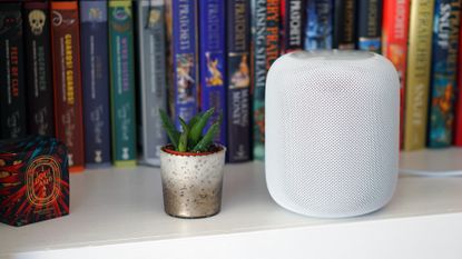 Apple HomePod on desk in front of books