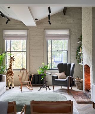 A painted brick wall, fireplace, armchair and quirky furniture illustrate beige living room ideas.