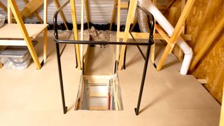 Boarded out loft with a focus on loft hatch opening with metal guard around the opening