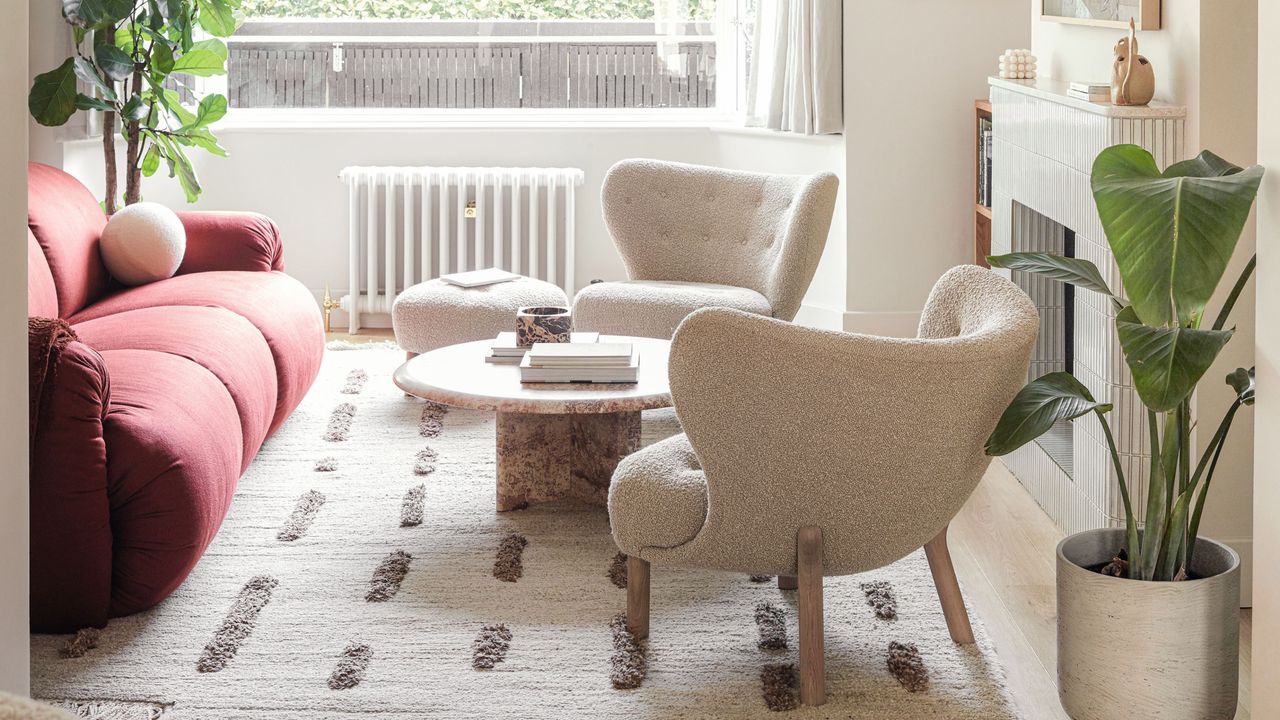 Netural living room with boucle armchairs, marble coffee table, and red sofa