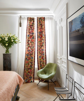 White bedroom looking onto window with white curtain and red detail sash