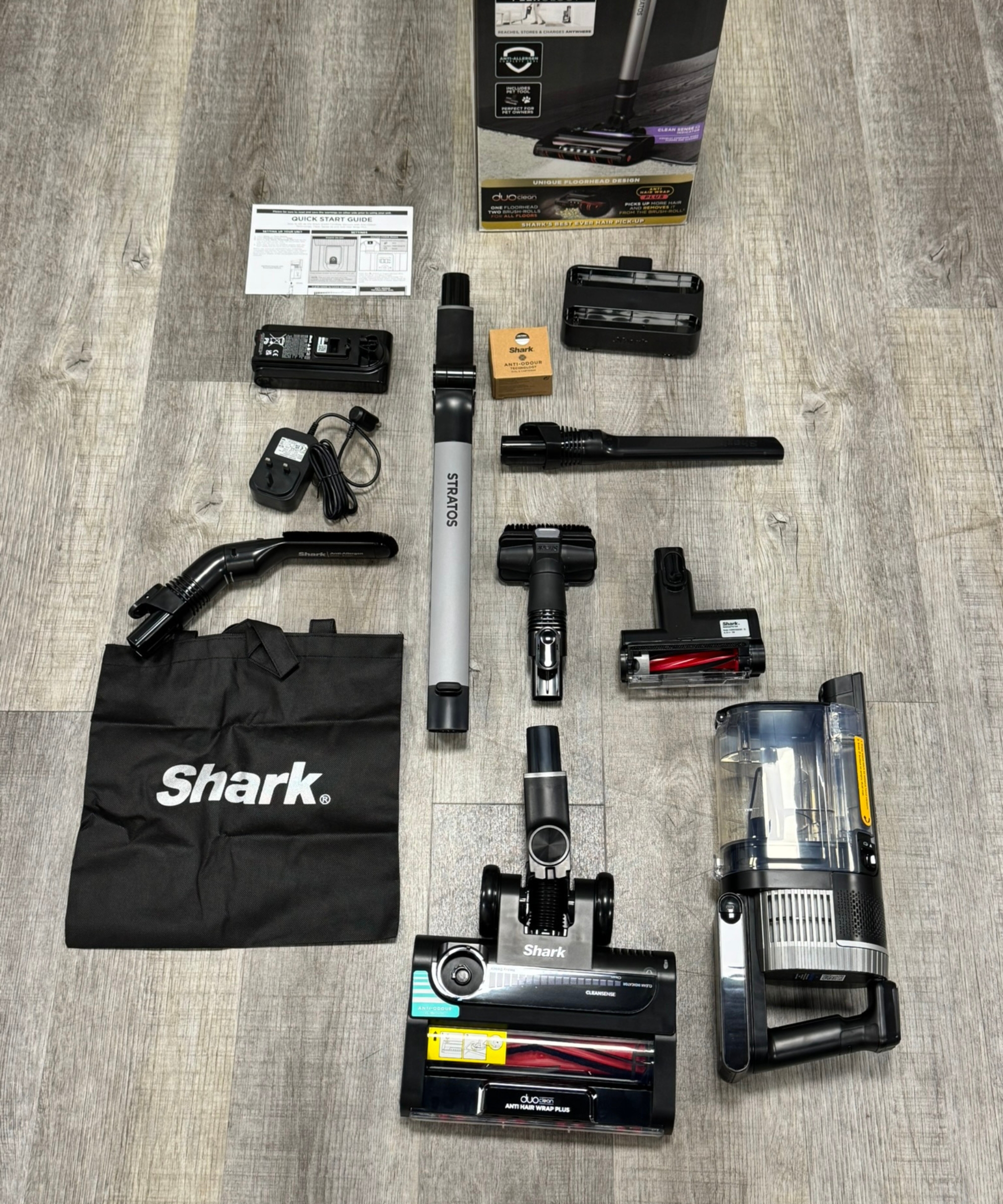 Every part and attachment for the Shark Stratos Cordless Vacuum laid out on gray laminate floor.