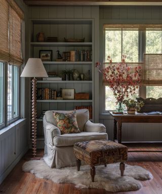 blue living room with panelled book shelves and a cozy reading nook with armchair and fur rug