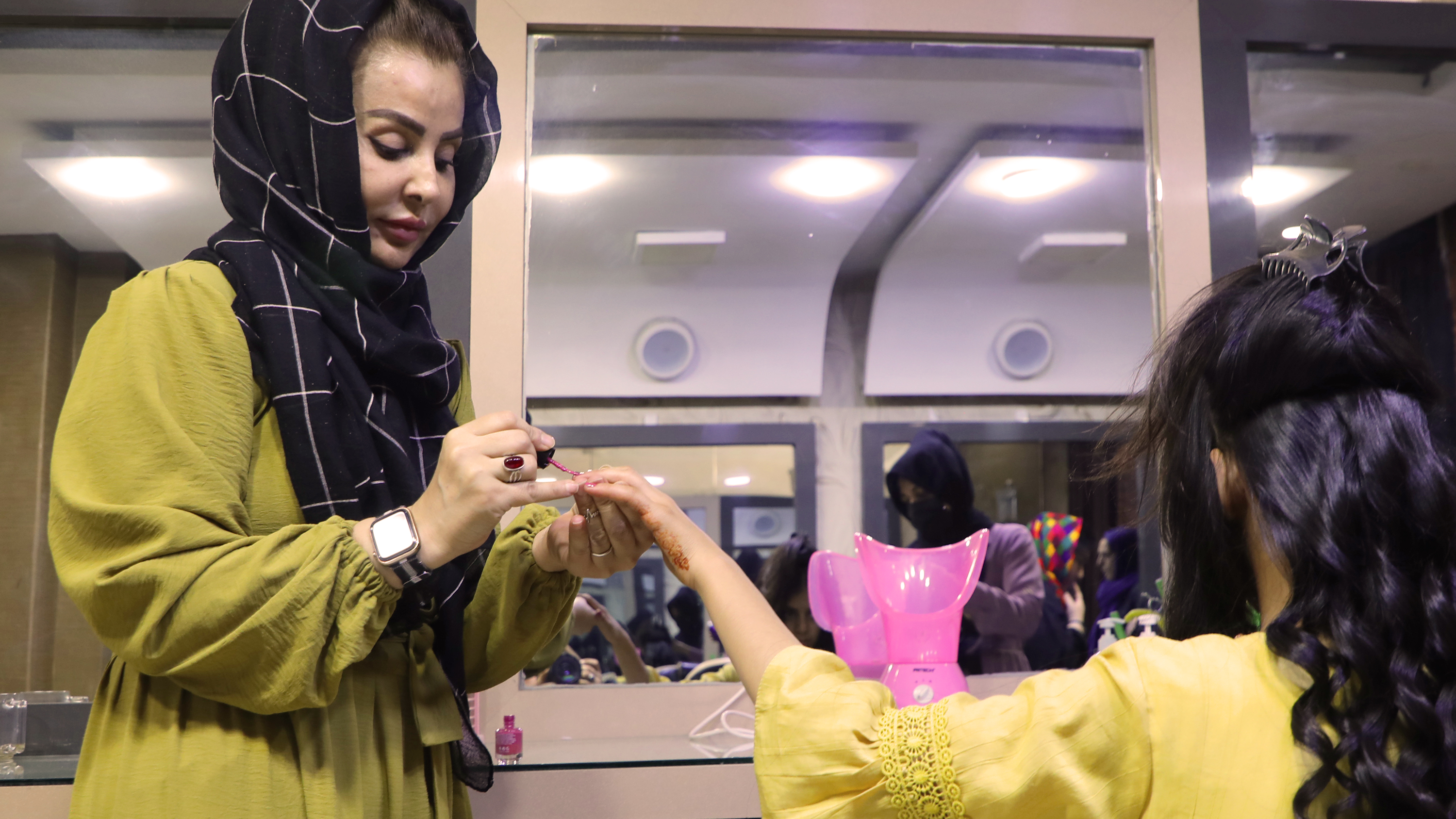 A salon owner in Kabul paints a client's nails