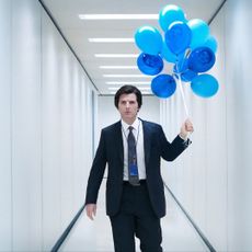 A still of Adam Scott holding blue balloons in 'Severance' season 2.