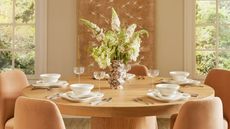 Round wooden table with taupe velvet chairs and cream crockery