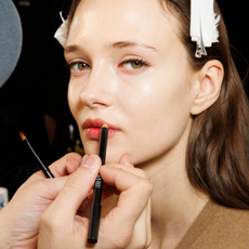 A makeup artist works on a model backstage ahead of the Luisa Spagnoli fashion show during the Milan Fashion Week Womenswear Fall/Winter 2024-2025 on February 25, 2024 in Milan, Italy. 