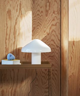 A white mushroom shaped lamp is shown on a wooden bookcase