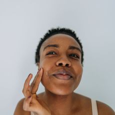 A woman applying one of the best spot treatments to her face