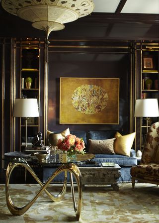 A living room with aubergine walls and gold accessories