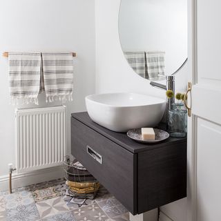 white wall with rounded mirror and sink and soap