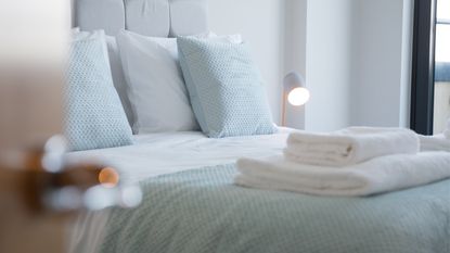 A set of white clean cotton towels are folded and place on a bed in a bedroom - for article on how to get rid of cockroaches in the bedroom