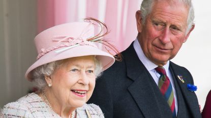 Queen Elizabeth wears a white tweed coat and a pink hat while her son Prince Charles wears a navy suit with a blue and red tie