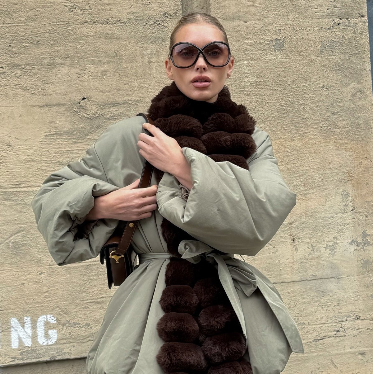 Elsa Hosk wearing a fur-trimmed parka, brown tights, and brown Alaia satin mules