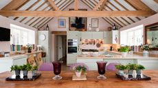 Open plan kitchen-diner with pitched wooden ceiling, wooden beams, and wooden dining table