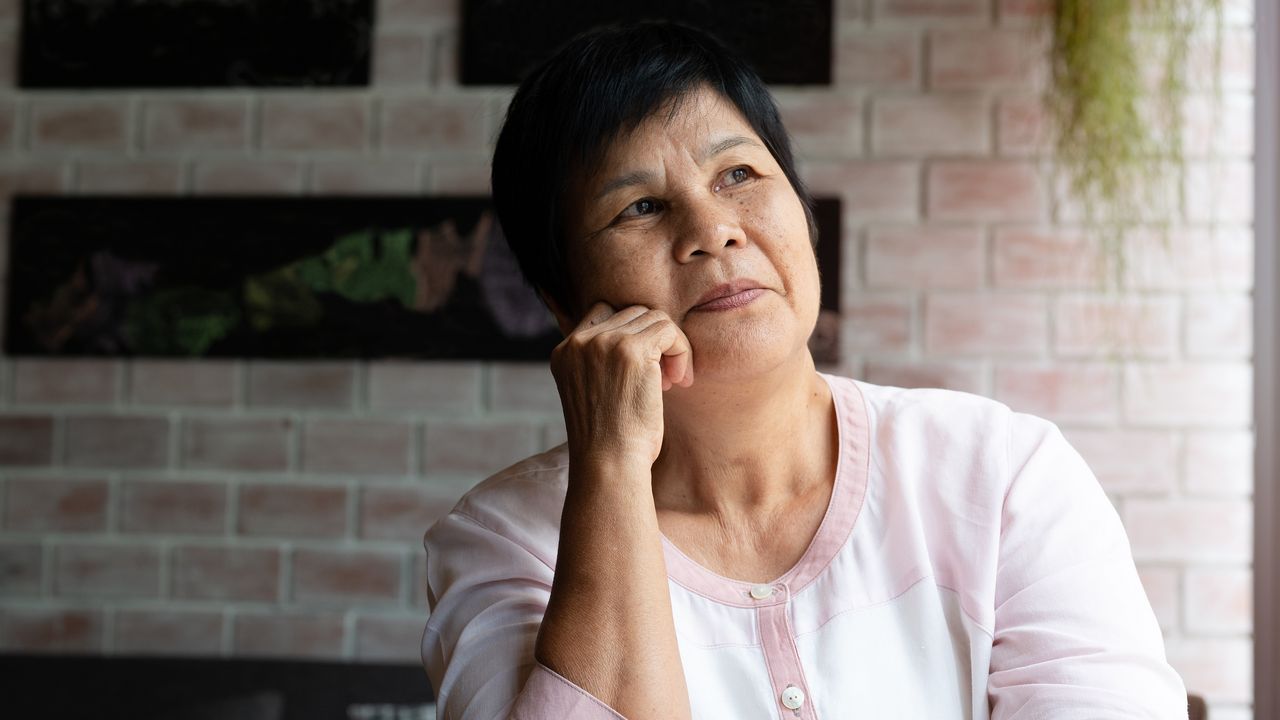 An older woman looks into the distance, clearly thinking.