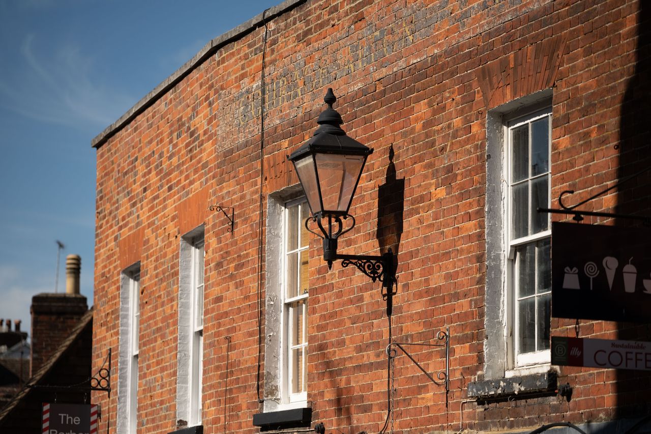 Viltrox AF 90mm F2.2 EVO lens image gallery: an old building at golden hour, stronf shadows cast onto the brick wall from a large street lamp