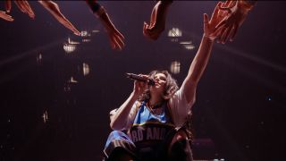 Billie Eilish from below, singing and reaching out to her fans in Billie Eilish Hit Me Hard And Soft The Tour (Live in 3D)