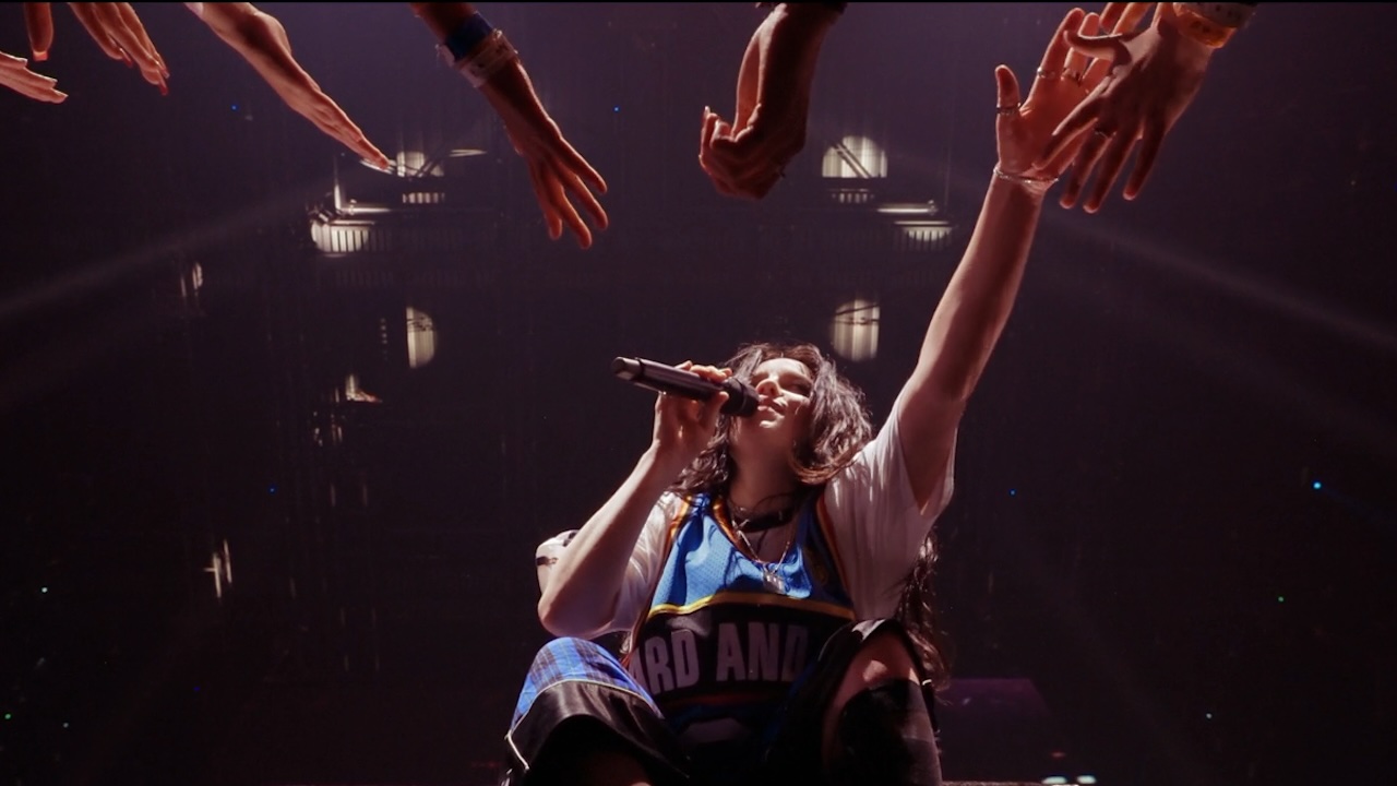 Billie Eilish from below, singing and reaching out to her fans in Billie Eilish Hit Me Hard And Soft The Tour (Live in 3D)