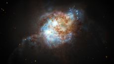 Two bright blue spheres representing supermassive black holes swirl amidst a cloud of blue and brown dust in the early universe