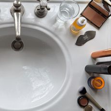 beauty products lined up on the side of a white porcelain sink