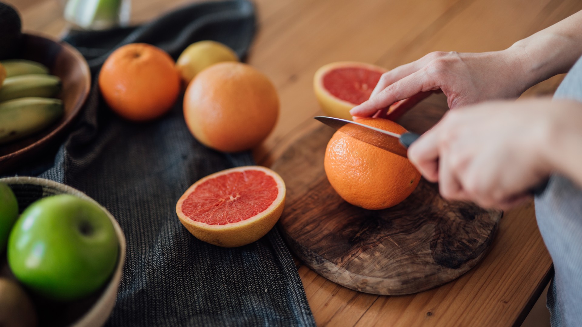 Person chopping up grapefruit on a chopping board