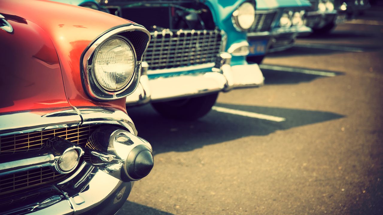 Front headlight detail of a row of classic cars