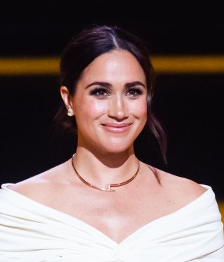 Meghan Markle smiling with closed lips at the camera