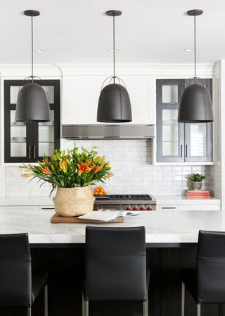 A black and white kitchen with a bright basket of flowers on the kitchen island.