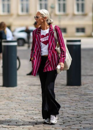 A guest wearing a red pinstripe blazer, graphic tshirt and flares at Copenhagen Fashion Week