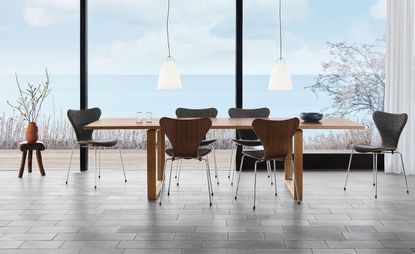 Long table with six Arne Jacobsen chairs by Fritz Hansen, in front of a large window overlooking the sea