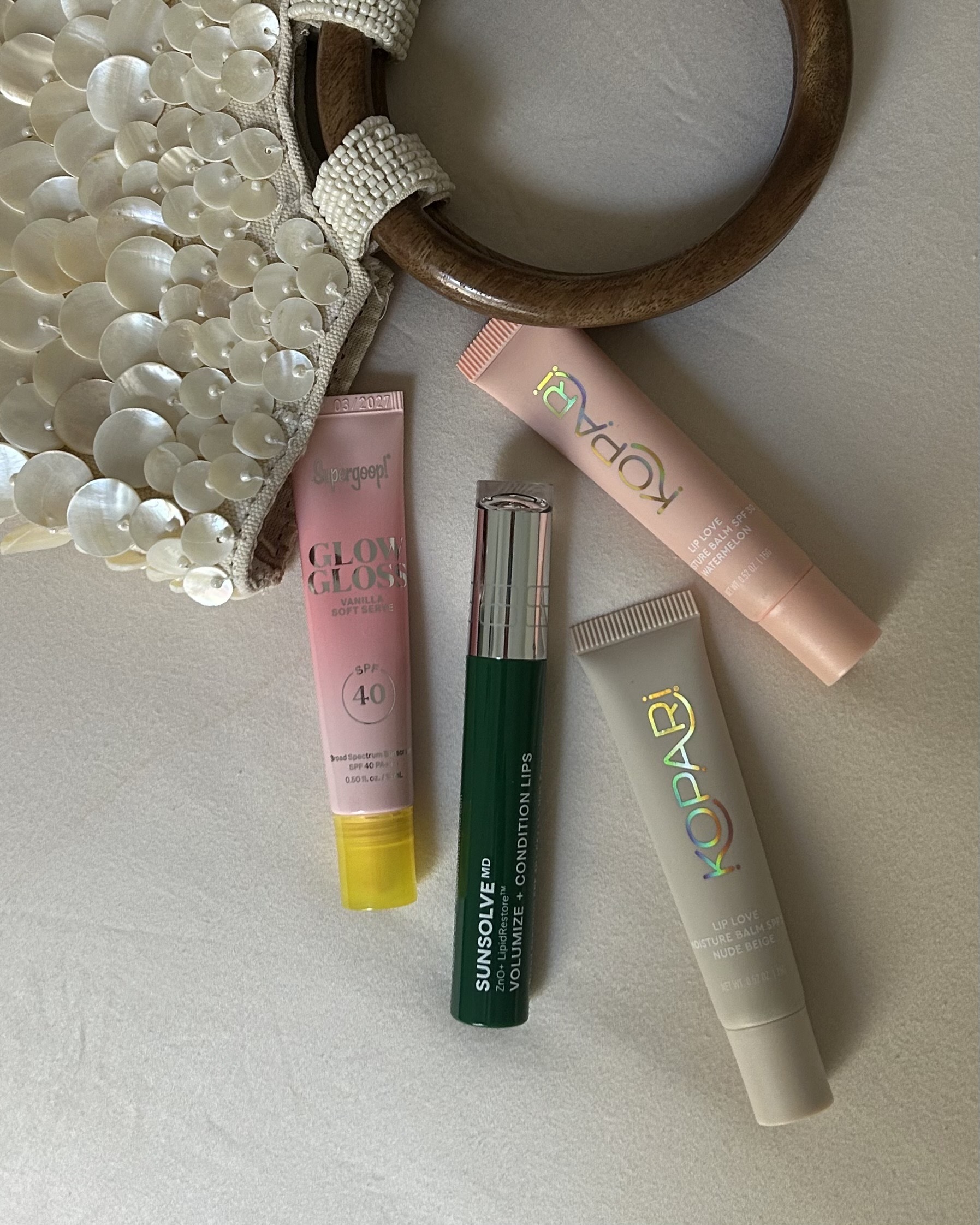 Image of lip balms with SPF spilling out of a seashell-adorned purse.