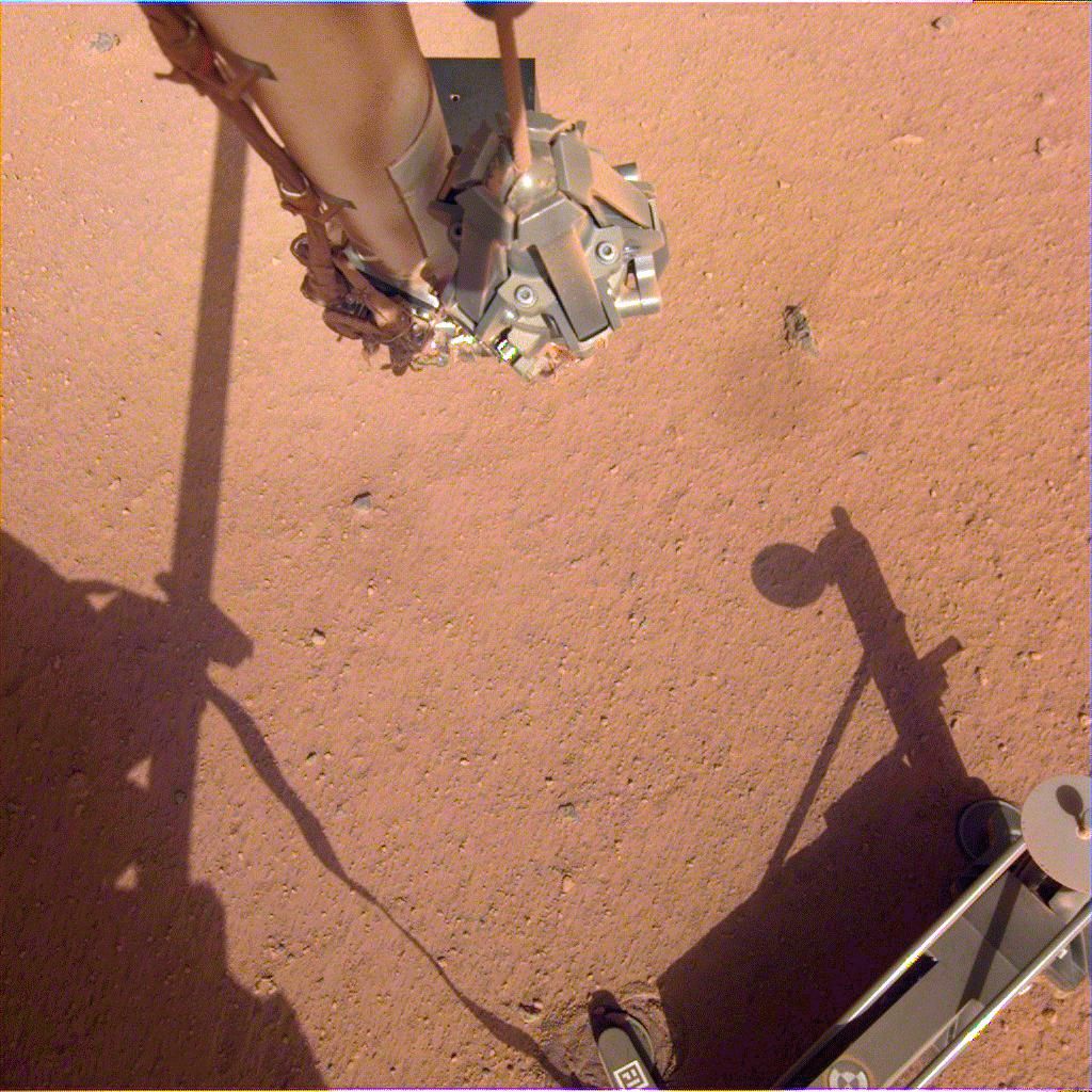 The robotic arm on NASA&#039;s Mars InSight lander moves in place over the Heat Flow and Physical Properties Package (HP3) and opens the fingers of its grapple in this image from June 1, 2019.