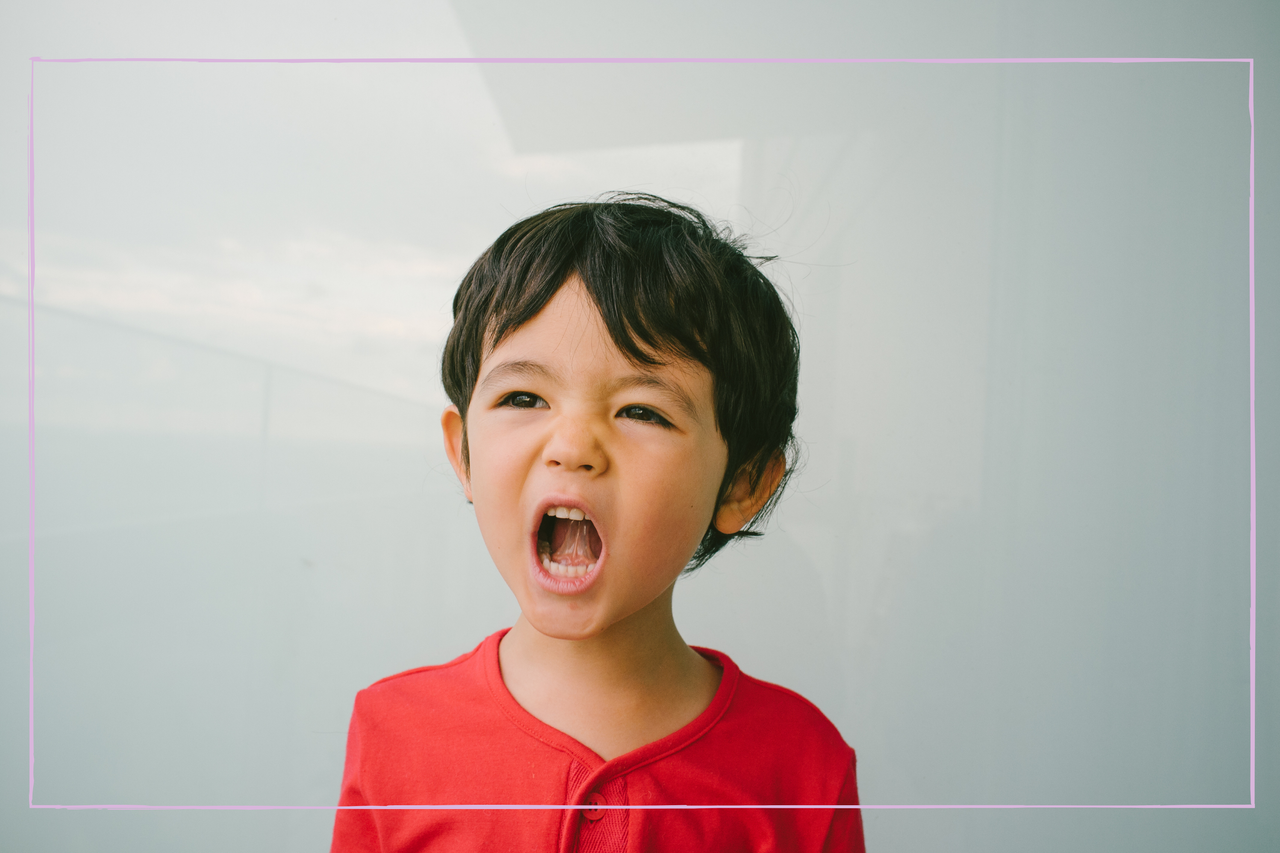 Portrait of a young boy wearing a red top, with his mouth open as if shouting