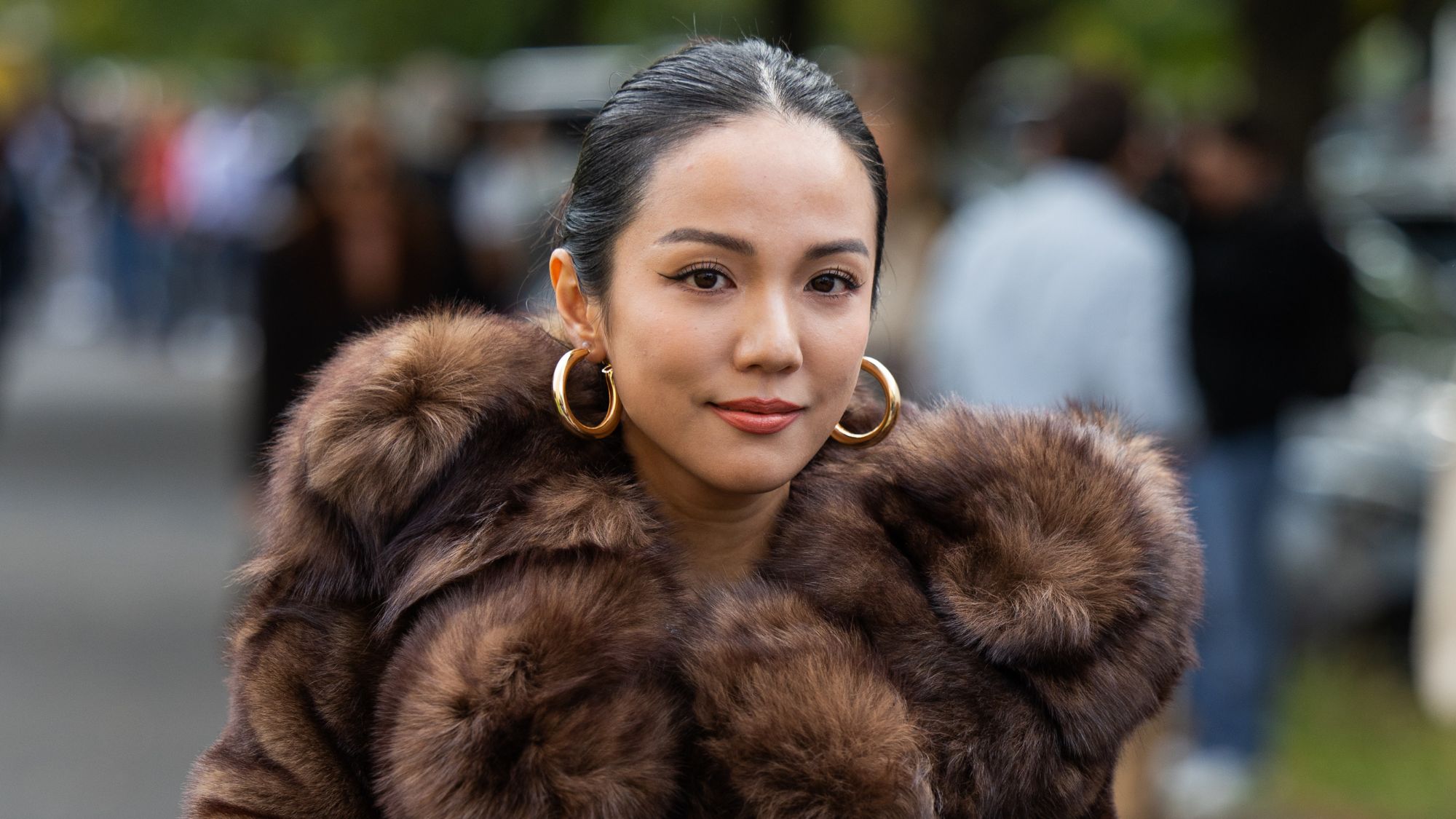 street style shot of woman wearing brown fur coat and gold hoop earrings