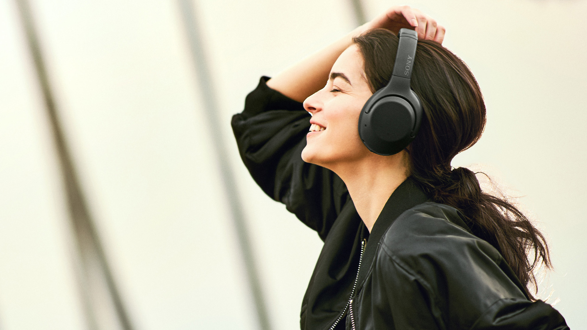 Woman wearing Sony XB900N headphones.