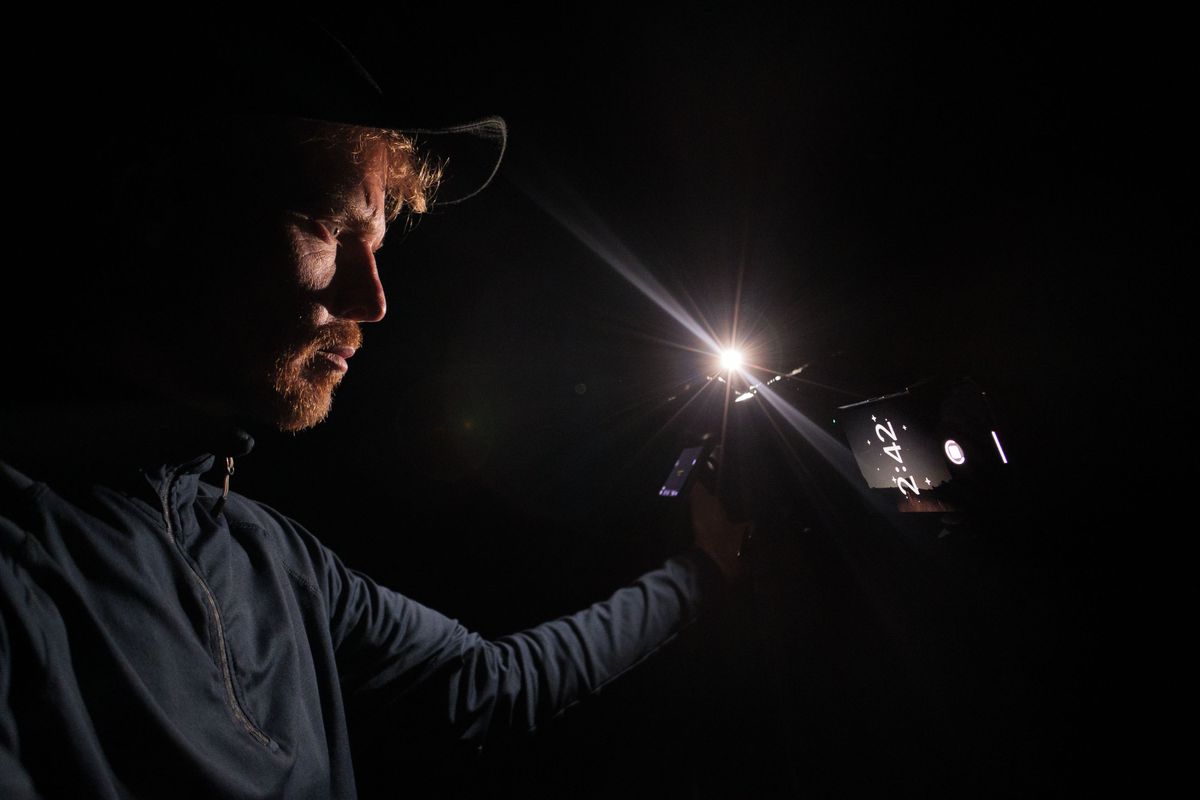 Pixel phone and Nikon mirrorless camera side by side mounted to tripods at night, with the astrophotography mode active on the Pixel and Tim Coleman controlling the camera