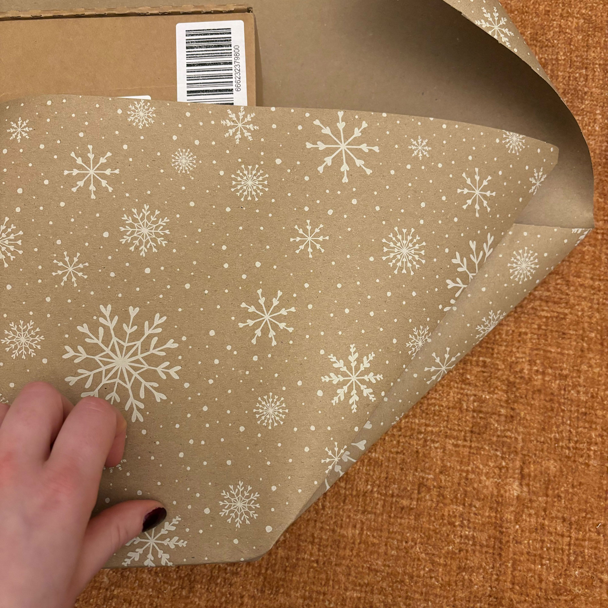 A rectangular box wrapped in brown paper with a white snowflake print on it