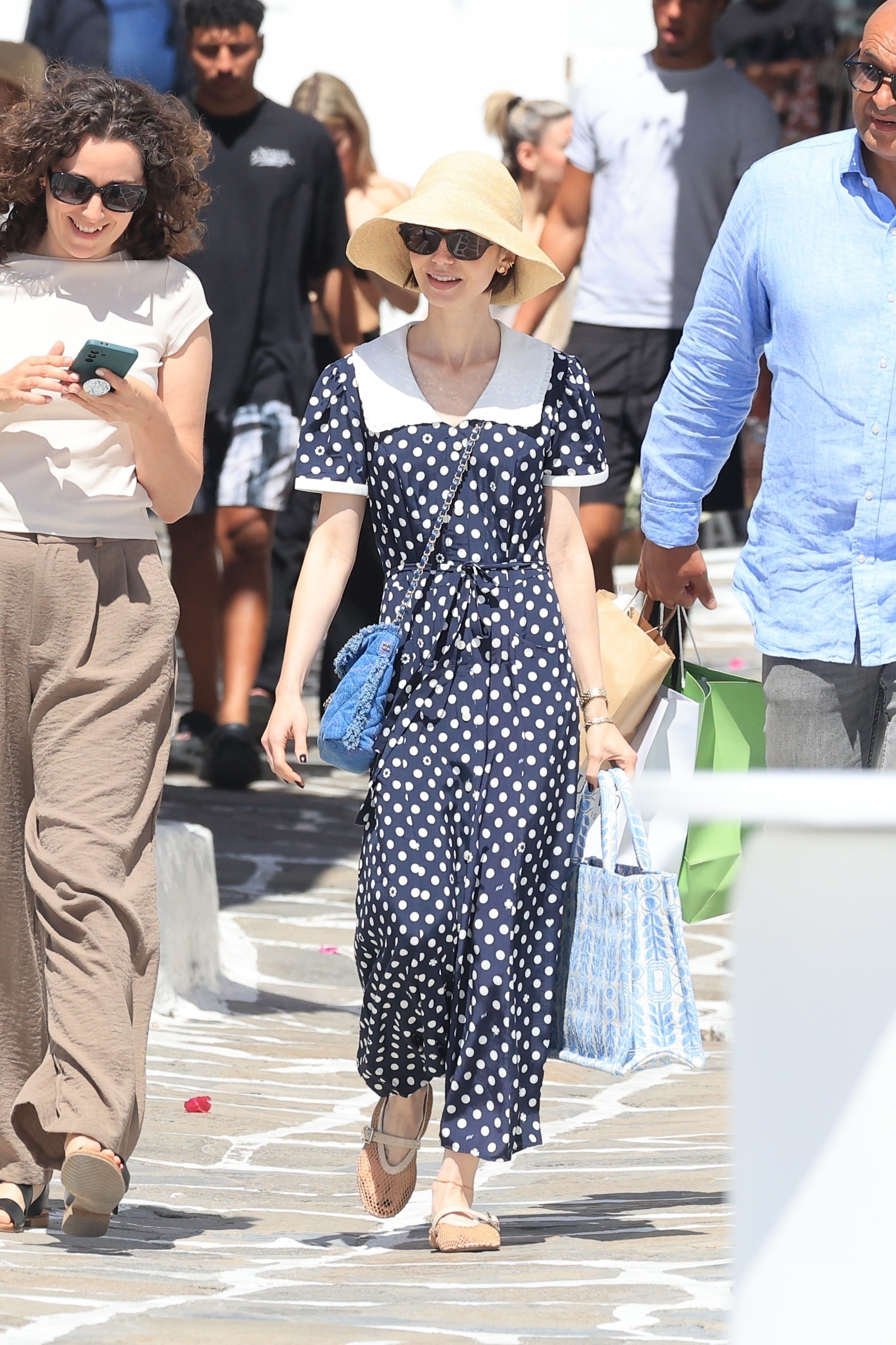 Lily Collins wears beige mesh ballet flats with a polka dot dress and a straw hat.