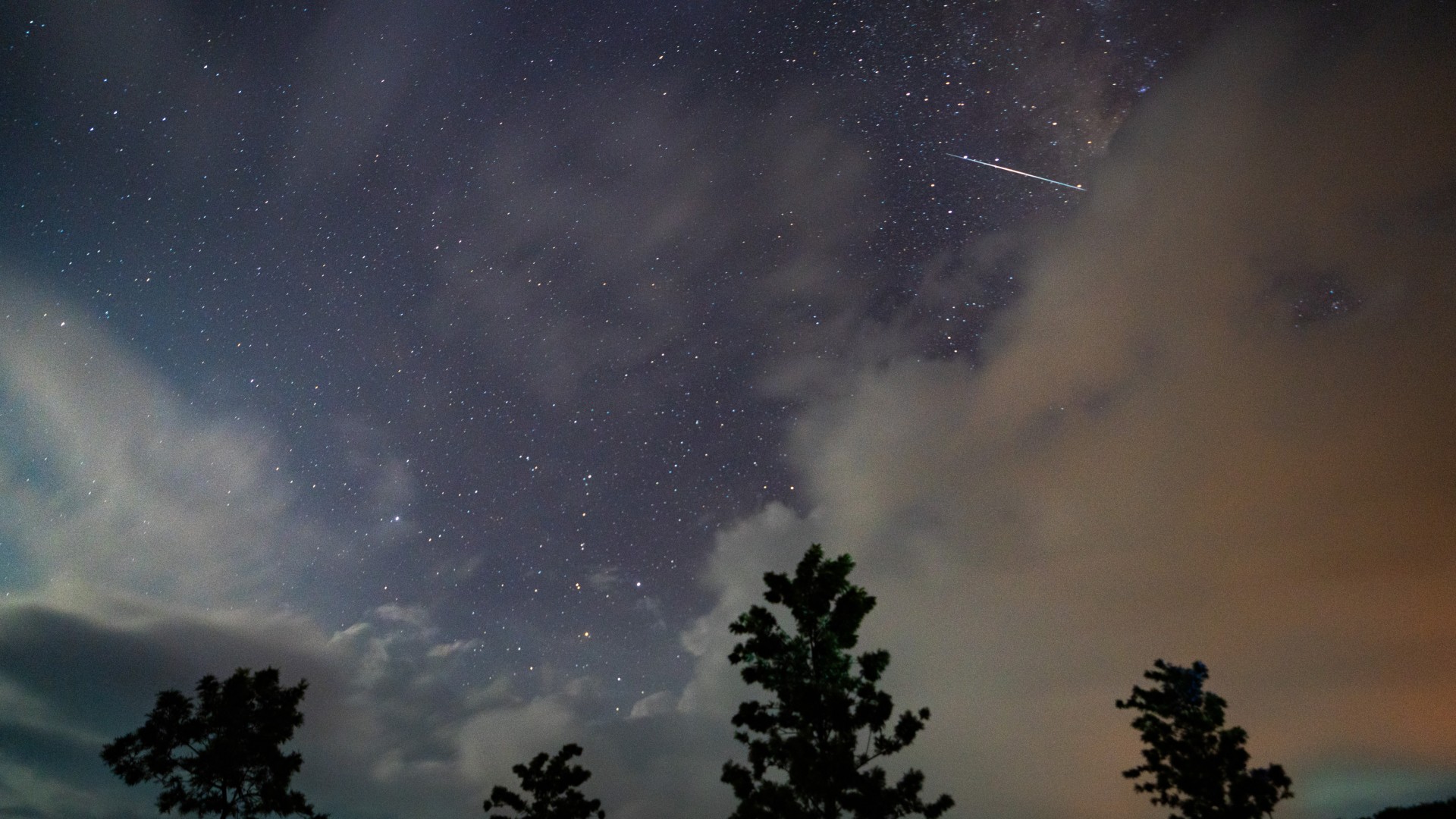 a streak of light races across a starry night sky