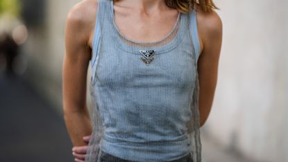  guest wears a white tank-top from Prada, a pale gray tank-top / red embroidered rhinestones / long dress from Prada, black shorts, outside Prada, during the Milan Fashion Week - Womenswear Spring/Summer 2023 on September 22, 2022 in Milan, Italy.