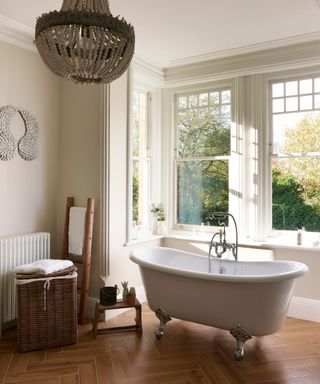 bathroom with freestanding bath in a large bay window and ornate chandelier