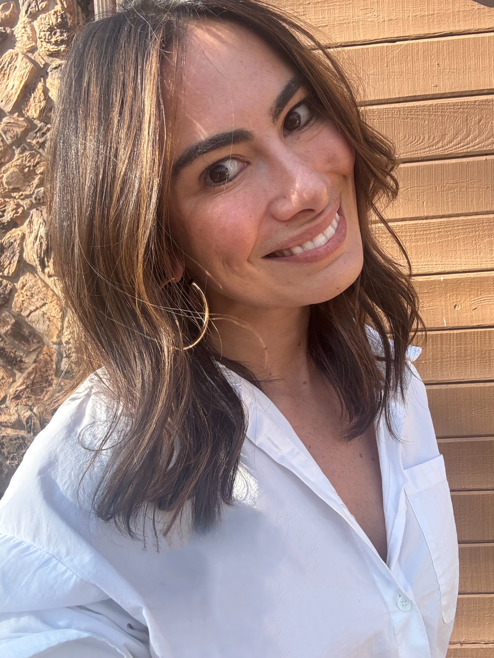 a white woman with medium length brown hair in a white shirt